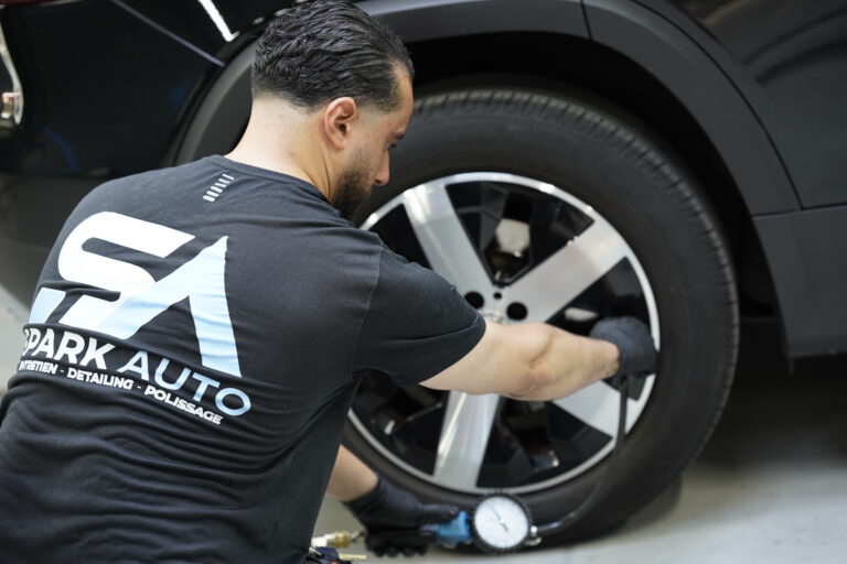 Technicien Spark Auto inspectant une roue au contrôle