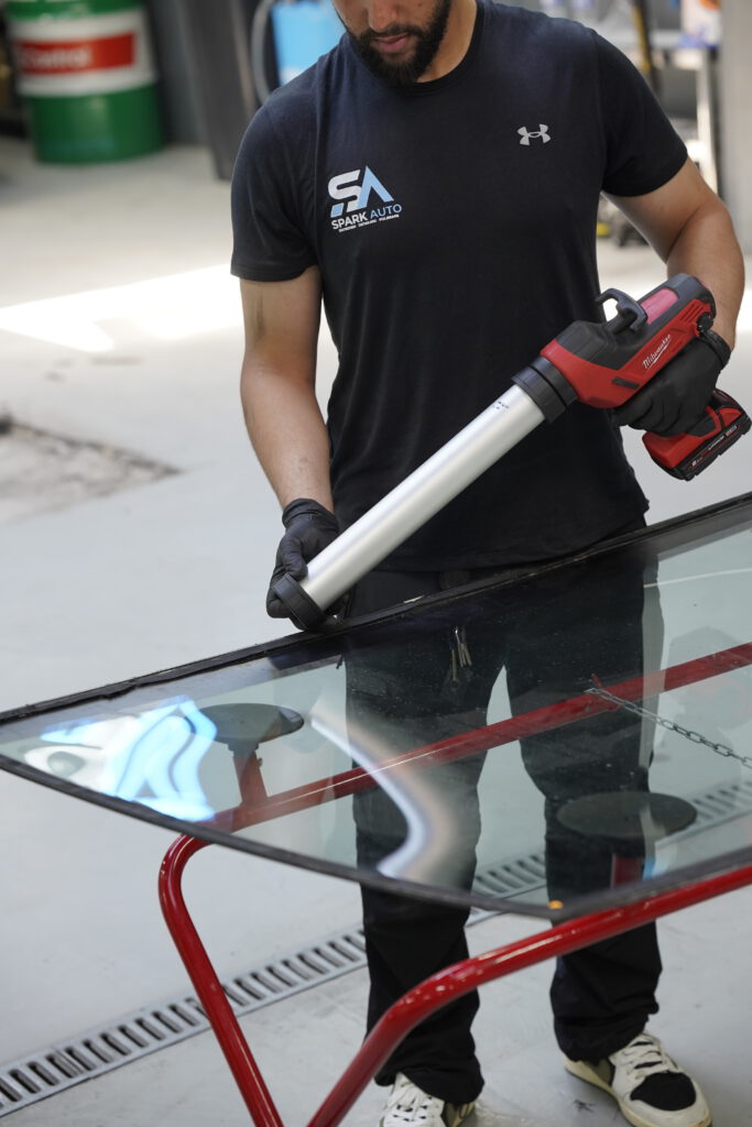 Technicien Spark Auto préparant un pare-brise au chevalet